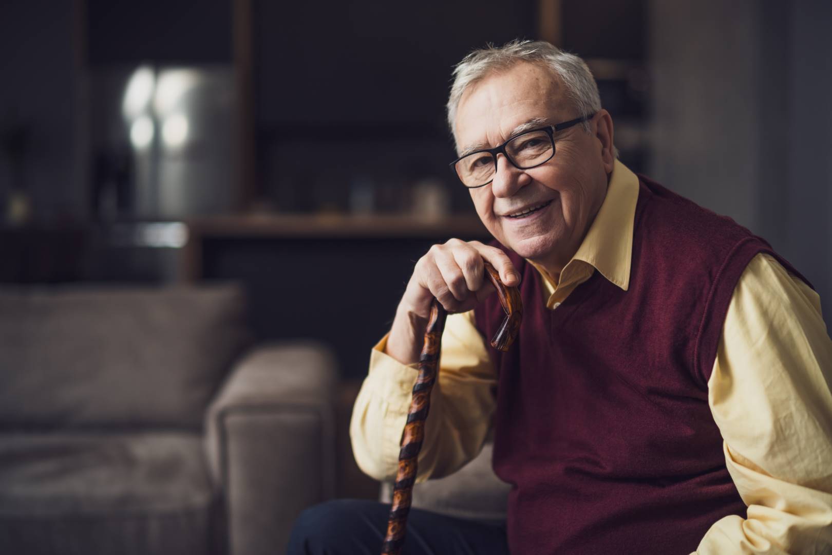 Senior man sitting at home with cane